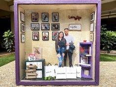 a man and woman standing next to each other in front of a wall with pictures on it