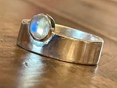 Because I just can't get enough of the monolith style ring, I've designed a 925 Sterling silver Rainbow moonstone ring that comes in sizes 4-13. Just trying to share the love here ;-) The stone: Rainbow moonstone Cabochon 6mm round The ring: Monolith with offset cabochon Shank is 6mm wide, 1.5mm thick Finish in either glossy or matte (brushed) - either is beautiful! This is certain to become one of your everyday rings! Need a quarter size? No problem, just message me! Ships within 5 business days. Arrives tastefully packaged for you to present as a gift to someone you care about . . . or to yourself! I always include a FREE GIFT in every shipment - a lovely Sunshine Cloth for keeping your piece clean and shiny.  Soap and water work well for in between Sunshine Cloth touchups. I take pride Handmade Modern Moonstone Ring For Anniversary, Modern Handmade Silver Moonstone Ring, Handmade Modern Moonstone Ring In Sterling Silver, Modern Handmade Sterling Silver Moonstone Ring, Modern Adjustable Moonstone Sterling Silver Ring, Artisan Cabochon Moonstone Gift Ring, Nickel-free Sterling Silver Moonstone Ring, Spiritual Gold Moonstone Cabochon Ring, 14k Gold Moonstone Ring Gift, Oval Cabochon