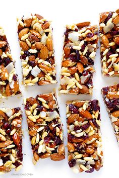 six bars with nuts and cranberry toppings cut into squares on a white surface