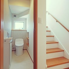 there is a toilet and some stairs in this bathroom with wood trim on the walls