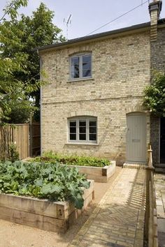 a brick house with garden beds in the front yard