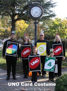 a group of people standing next to each other holding signs and a clock in the background