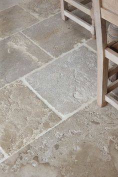 a wooden bench sitting on top of a stone floor next to a table and chair