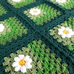 a crocheted blanket with white and green flowers