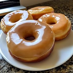 three glazed donuts on a white plate