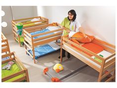 a woman sitting on top of a wooden bunk bed next to another child's bed