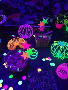 glow in the dark birthday party supplies and decorations on a black table with bright lights