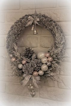 a christmas wreath hanging on a brick wall with bells and pineconis around it