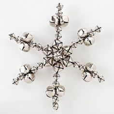 a silver snowflake with bells hanging from it's sides on a white background