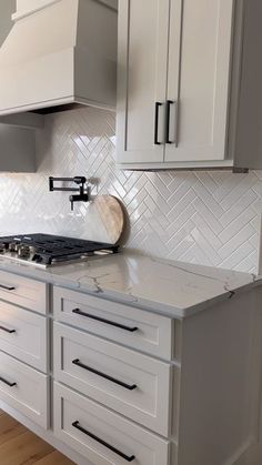 a kitchen with white cabinets and marble counter tops, along with a stove top oven