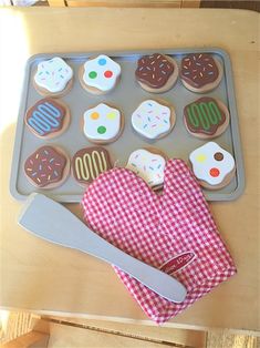 an assortment of decorated cookies and pastries on a cookie sheet with a knife next to it