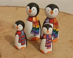 three penguin figurines are standing next to each other on a piece of wood