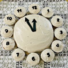 cupcakes with white frosting and black numbers arranged in a circle on a table