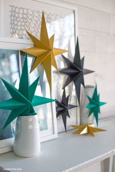 five paper stars are placed on a shelf next to a vase with one star in it