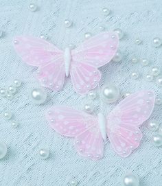 three pink butterflies with white pearls on a table