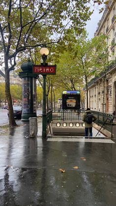 a person with an umbrella is standing in the rain near a bus stop on a rainy day