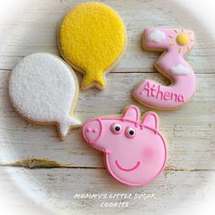 three decorated cookies sitting on top of a white plate with pink and yellow frosting