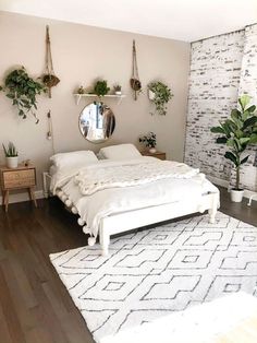 a white bed sitting on top of a hard wood floor next to a wall mounted mirror