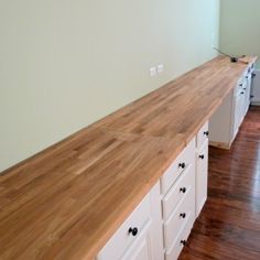 an empty kitchen with white cabinets and wood counter tops in the middle of the room