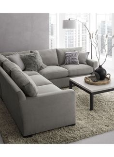 a living room with a large sectional couch and coffee table in front of a window