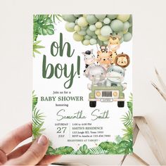 a baby shower with jungle animals on the front and green leaves in the back, is held up by a person's hand