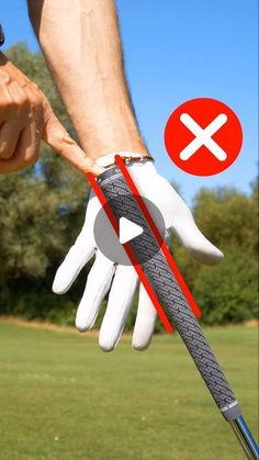 a person holding onto a golf club with a red and white x sign on it