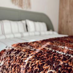 the bed is made up with white and brown blankets on it's headboard