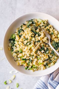 a white bowl filled with rice and vegetables on top of a blue and white towel