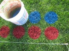 four red, white and blue balls are on the grass next to a plastic bucket