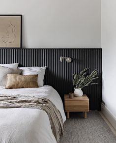 a bed with white linens and pillows in a bedroom next to a painting on the wall