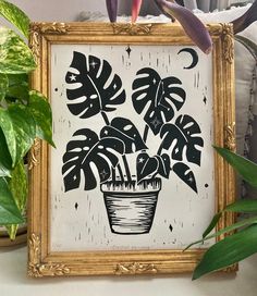 a painting of a potted plant in a gold frame on top of a table