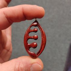 a person holding a small wooden brooch with the word love in it's center