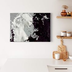 a white and black painting on the wall above a kitchen counter with wooden utensils