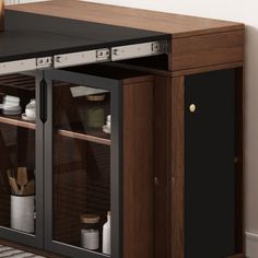 a kitchen cabinet with glass doors on the top and bottom, in front of a white wall