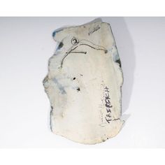 a piece of pottery with writing on the bottom and sides, sitting on a white surface