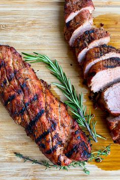 sliced pork on a cutting board with rosemary garnish