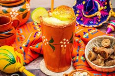 an orange drink with a lime on the rim and other mexican decorations around it,