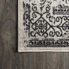 a white rug with black and grey designs on the bottom, sitting on a wooden floor