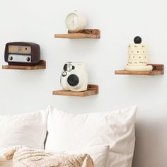 there are three wooden shelves on the wall above the bed, and one shelf is holding an alarm clock