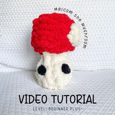 a crocheted stuffed animal with a red hat on it's head sitting on a bed