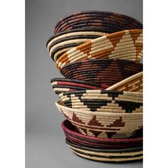 four woven baskets stacked on top of each other in different colors and sizes, all with designs