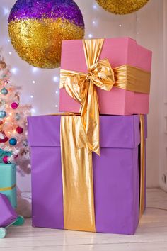 purple and gold wrapped presents in front of a christmas tree