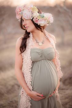 a pregnant woman with flowers in her hair is wearing a flower crown and posing for the camera