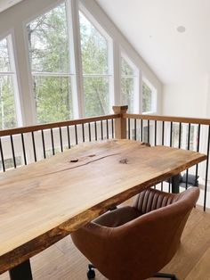 a wooden table sitting in the middle of a room next to a brown leather chair