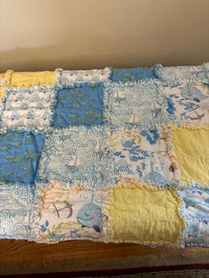 a baby quilt is laying on top of a wooden bed with blue, yellow and white squares