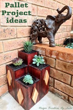 an elephant statue sitting next to three planters with succulents in them