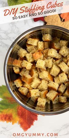 a metal bowl filled with stuffing cubes on top of a marble countertop next to an autumn leaf