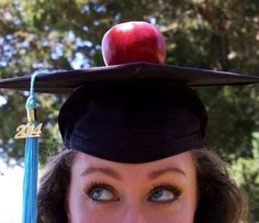 a woman wearing an apple on top of her graduation cap