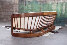 a wooden bench sitting on top of a cement floor next to a green wall and white cowhide rug