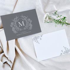 an elegant monogrammed wedding stationery is displayed on a bed